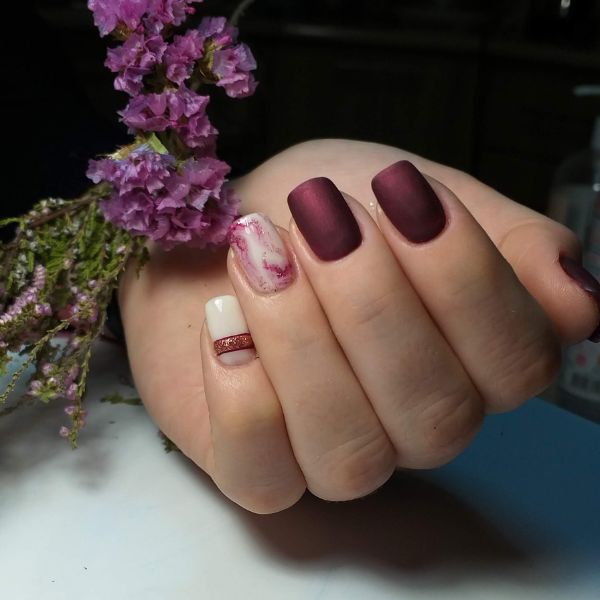 Unhas com efeito velvet nails em esmalte de cor marsala em fundo escuro