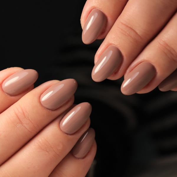 Foto de mãos com unhas marrom finalizadas com top coat para dar brilho, ideais para o outono.