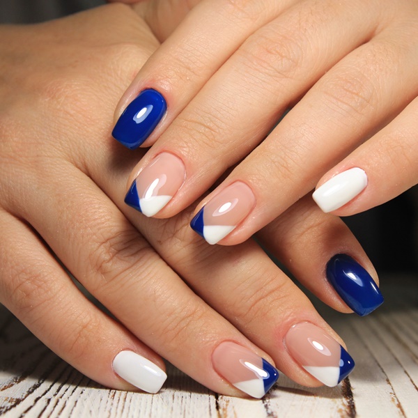 Modelo com unhas pintadas de azul escuros e detalhes branco