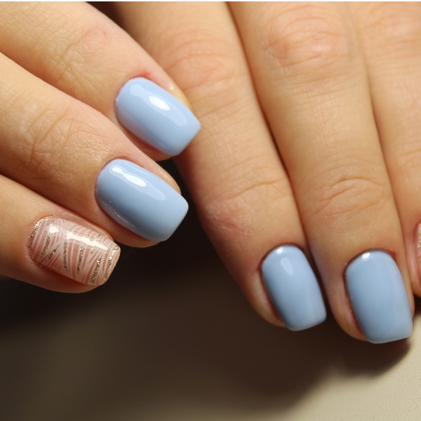 Modelo com unhas pintadas de azul claro e detalhes com brilho