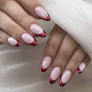 Mãos com unhas amendoadas e francesinha vermelha sobre base nude