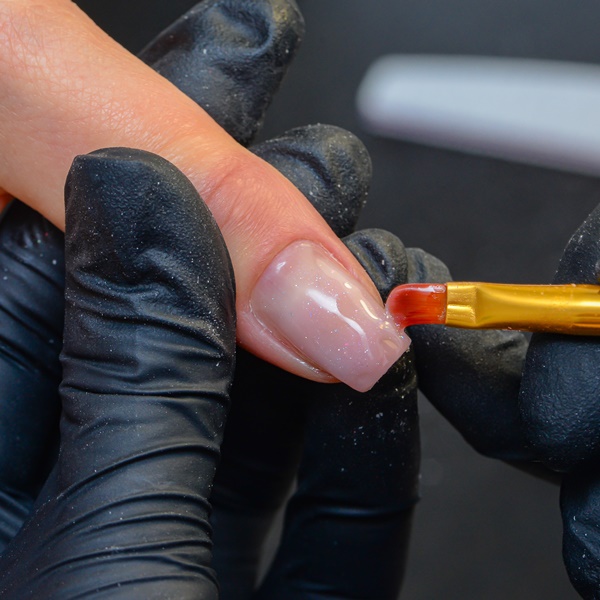 Nail designer aplicando gel sobre a unha