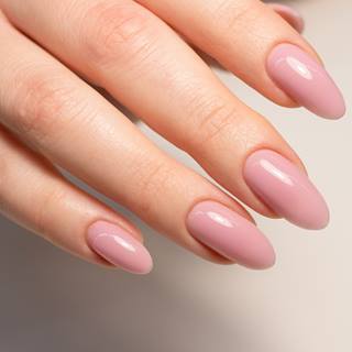 Unhas perfeitas feitas em casa com esmalte rosa claro.