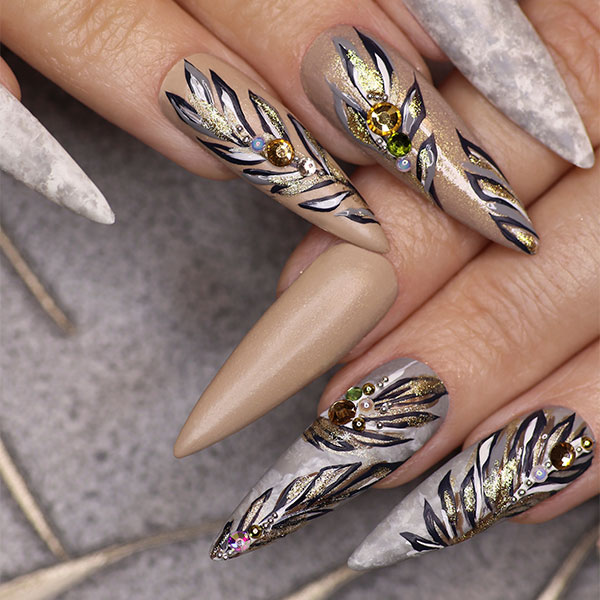 Mulher com unhas decoradas nude com folhas dourados