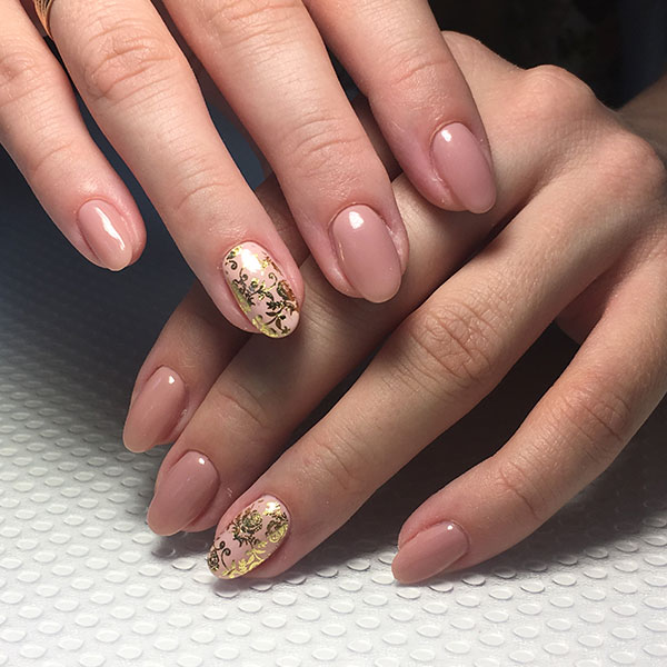 Mulher com unhas decoradas nude com dourados