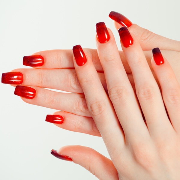 Modelo com unhas degradê no tom de vermelho