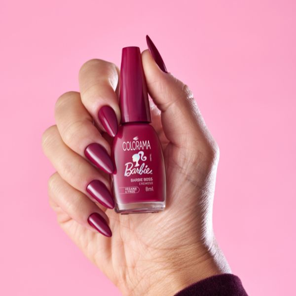 Foto de mão com o esmalte Barbie Boss nas unhas segurando o potinho do esmalte para mostrar para a câmera.