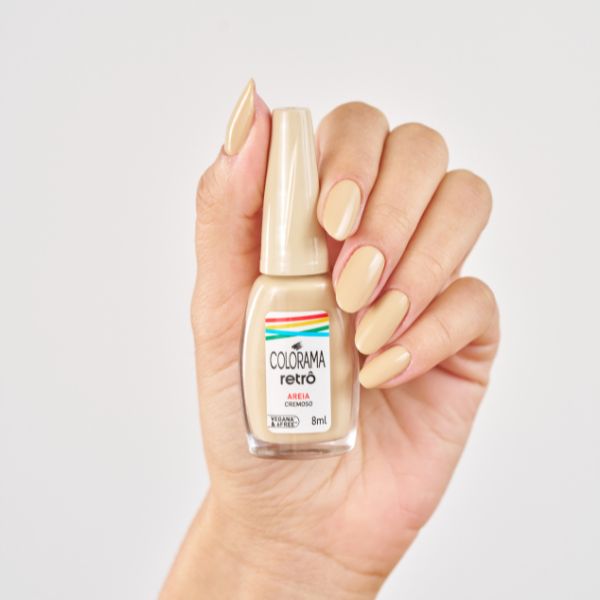 Mão segurando o esmalte Areia da Coleção Colorama Retrô.