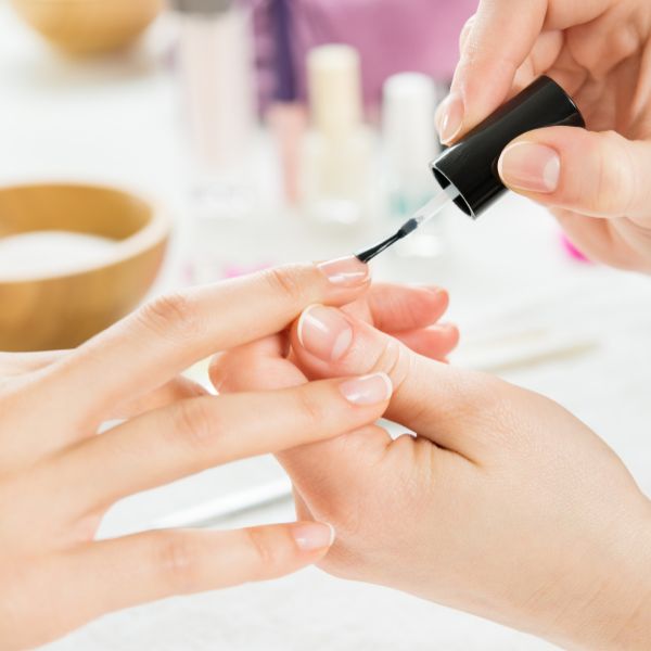 Manicure passando base crescer unha na cliente.
