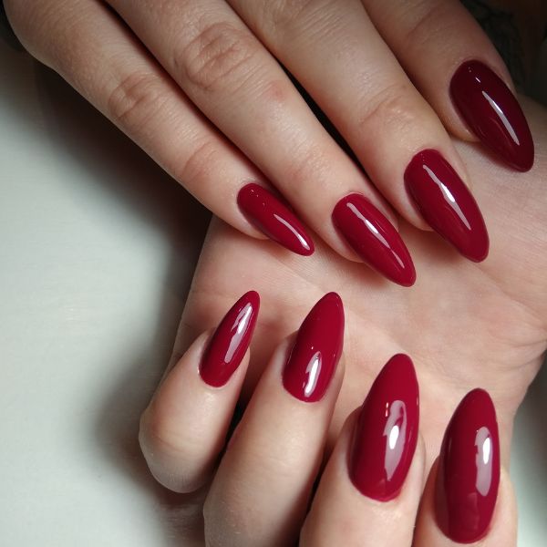 Mão com esmalte vermelho escuro nas unhas. 