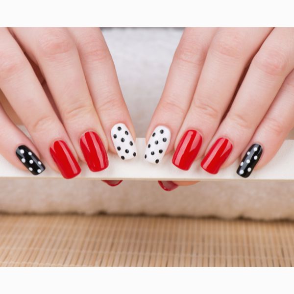 Unhas com esmalte vermelho, preto e branco com bolinhas poá.