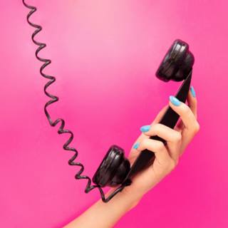Mão com unha azul segurando um telefone fixo.