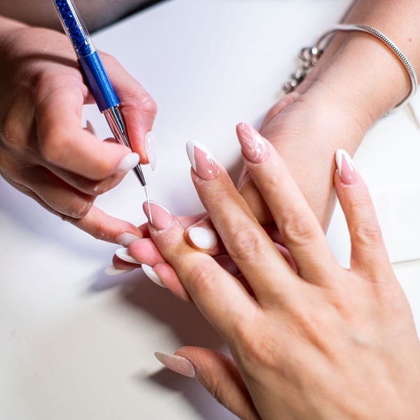 Manicure fazendo nail art na unha de sua cliente.