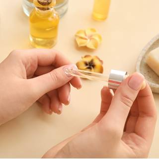 Mulher passando óleo de coco de babaçu nas unhas.