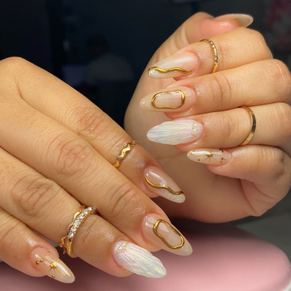 Mãos com press on nails com nail art dourada nas unhas.