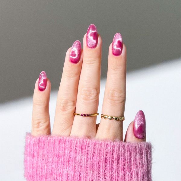 Mão com press on nails com unha encapsulada em tom rosa pink e dois anéis no dedo do meio e dedo anelar