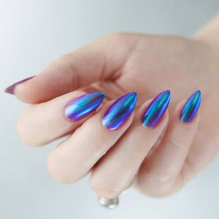 Mão com unha cromada degradê em tons de azul e roxo.