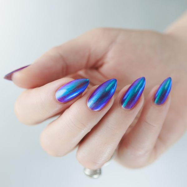 Mão com unha cromada degradê em tons de azul e roxo.