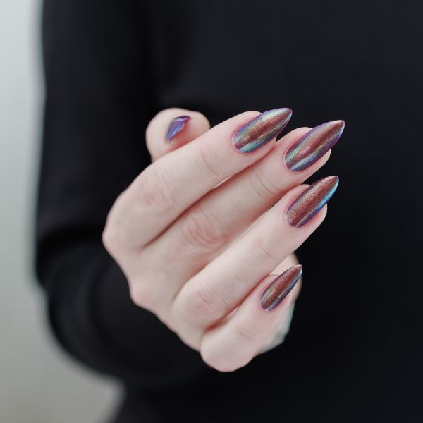 Mão com unha cromada em tons holográficos de azul, rosa e roxo.