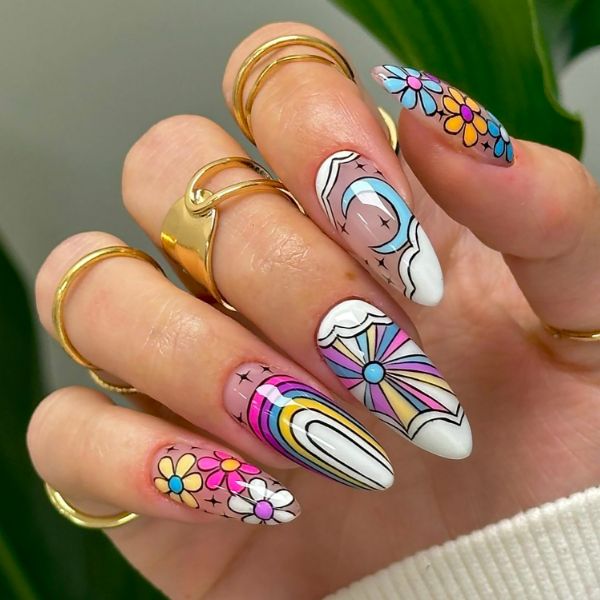 Unhas decoradas para carnaval com desenhos de arco-íris, nuvens e flores coloridas em tons pastel.