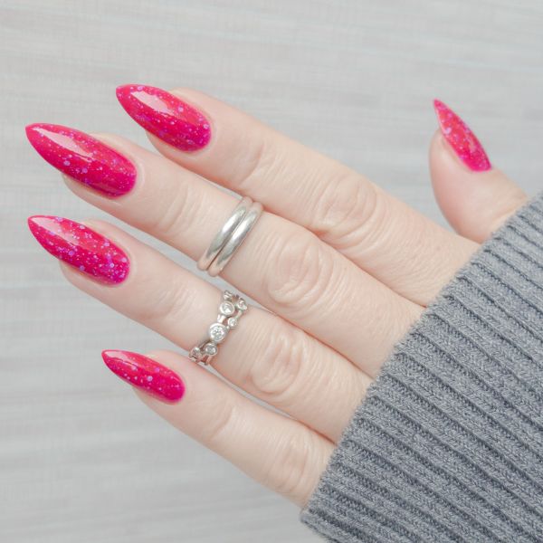 Unha com glitter rosa e anéis em prata. 