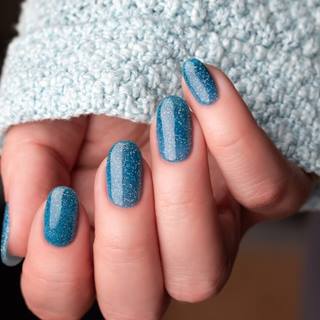 Unhas encapsuladas azul com glitter prata.