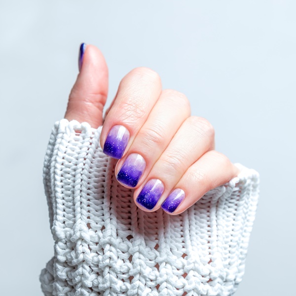 Mãos com degradê com glitter nas unhas.