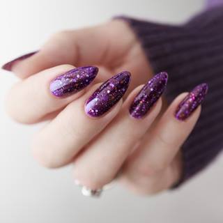 Mão com unha com glitter roxo.