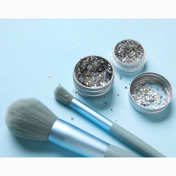 Pincéis e potes com glitter prata.