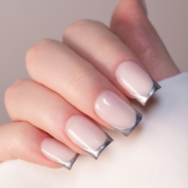 Mão com unhas simples usando francesinha moderna com ponta metálica prata.