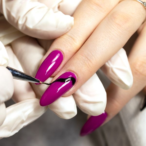 Profissional manicure pinta as unhas alongadas com alongamento de unhas de sua cliente.