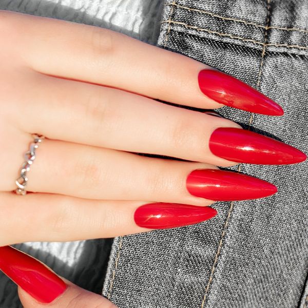 Unhas vermelhas em fundo de tecido jeans é uma das cores de unhas do momento.