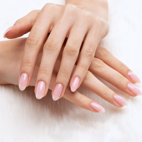 Unhas delicadas em tom neutro e nude em fundo branco.