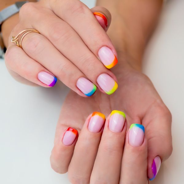Unhas pintadas em estilo francesinha colorida.