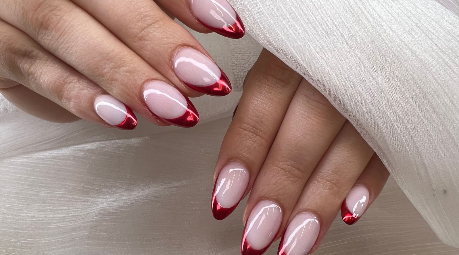 Mãos com as unhas pintadas de francesinha com a ponta em vermelho.