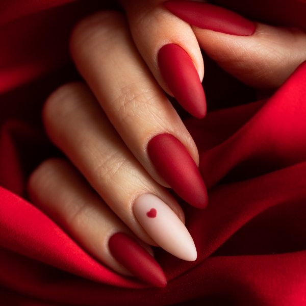 Foto da mão de uma mulher com as unhas vermelho intenso e vibrante, em formato acentuado e longo.