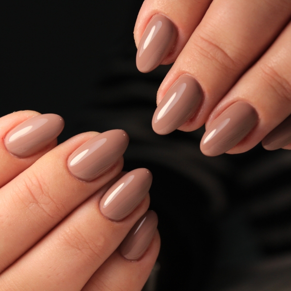 Foto de mãos com unhas marrom finalizadas com top coat para dar brilho, ideais para o quiet luxury.