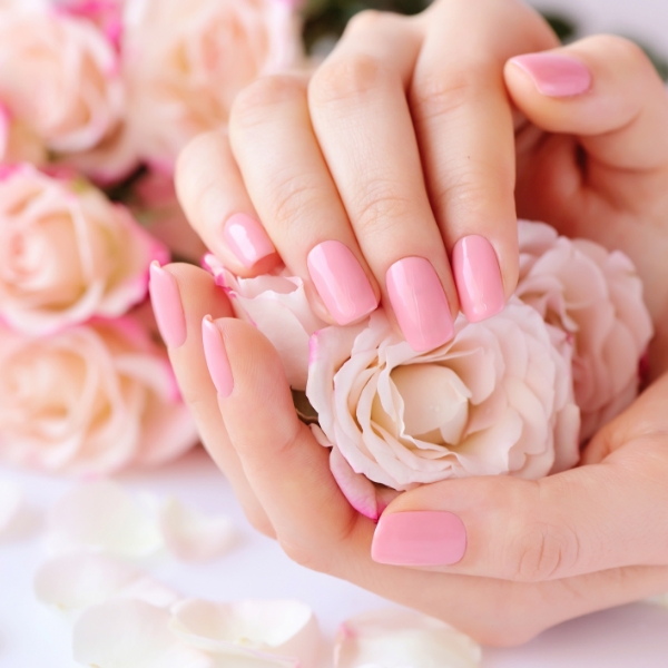 Foto mãos segurando uma rosa branca com unhas estilo quiet luxury em cor rosa delicado.