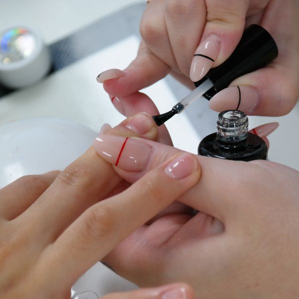 Manicure aplica esmalte nas mãos de uma cliente que pode ser seco com spray secante de unhas.