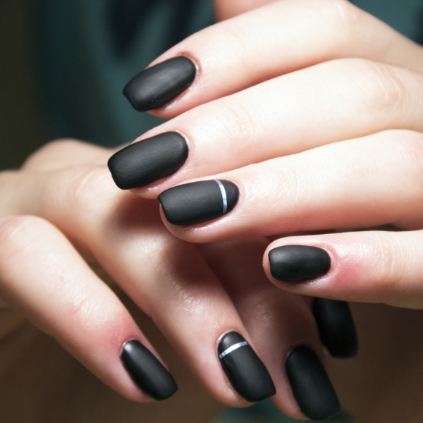 Mãos de uma mulher com as unhas pretas feitas com esmalte matte de acabamento fosco.