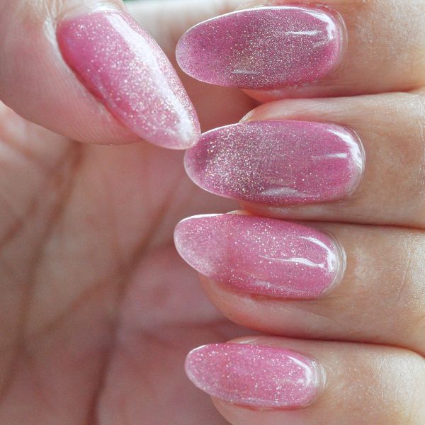 Profissional aplicando o esmalte cor de rosa para criar as unhas decoradas rosa em sua cliente