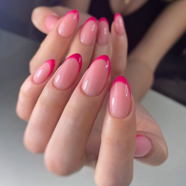 Foto de mão com o esmalte rosa claro e escuro, formando as unhas rosa francesinha