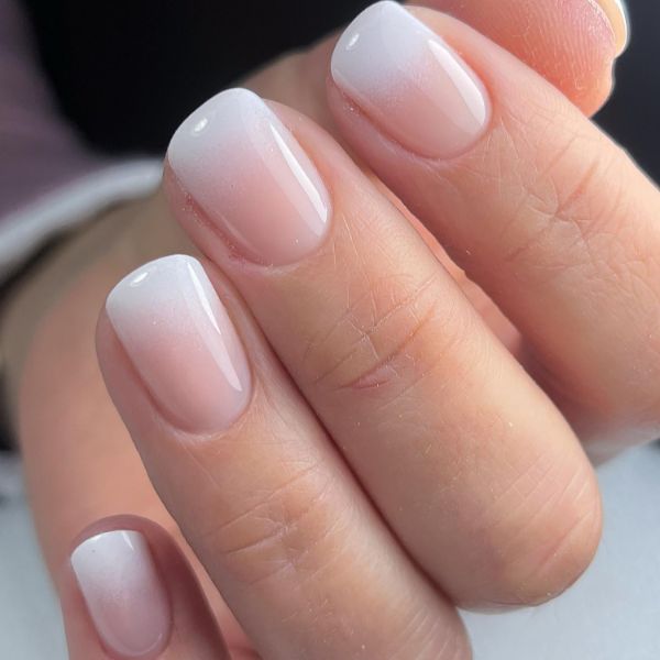 Unhas elegantes e curtas com esmalte nude rosado natural.